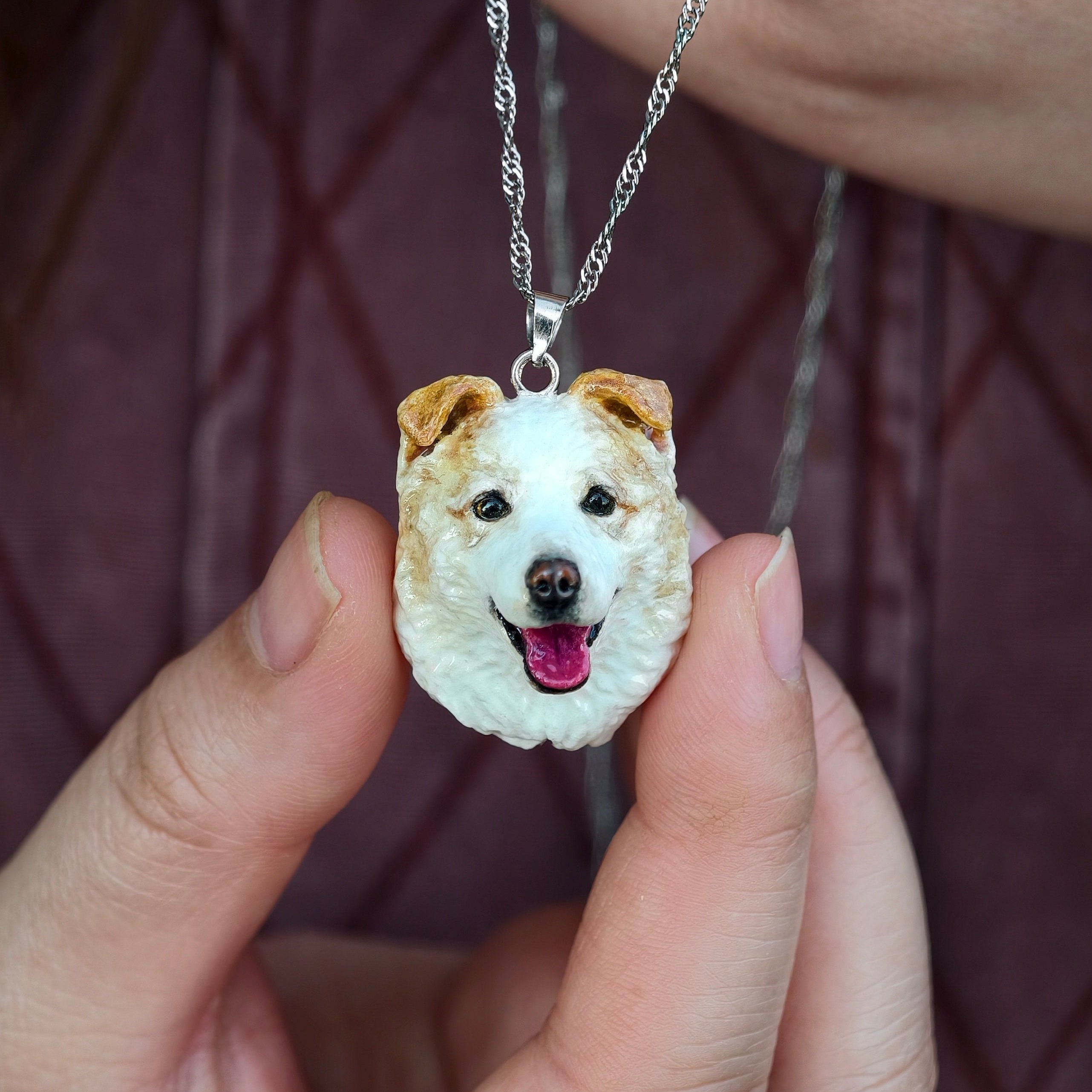 Custom clay cat portrait necklace next to real cat, silver-colored metal chain